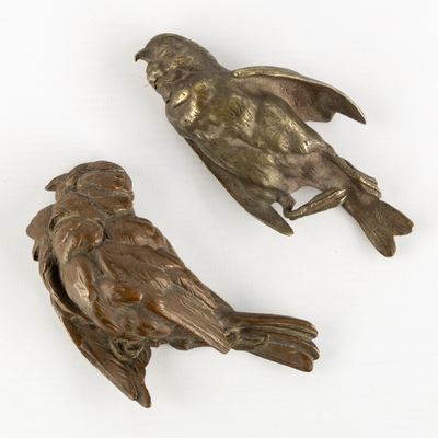 deux oiseaux en bronze posés l'un sur l'autre sur une surface blanche