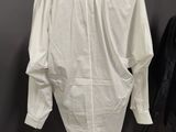 a white shirt on a mannequin stand in front of a gray wall