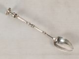 a silver spoon with a handle on a white surface