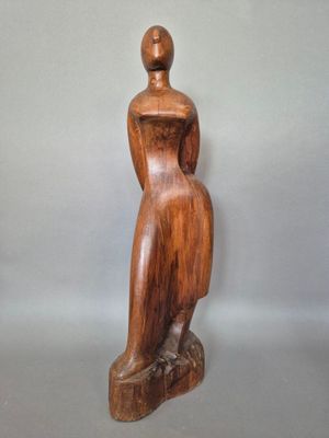 sculpture en bois représentant une femme assise sur un rocher, de dos par rapport à la caméra
