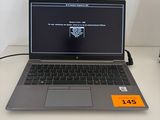 un ordinateur portable posé sur un bureau, à côté d'une lampe