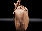 a tan purse with a zipper on it on a black surface