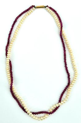 deux rangs de perles rouges et blanches, avec un fermoir doré, sur fond blanc