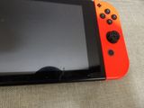 an orange and black nintendo switch lite sitting on top of a couch