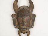 a metal mask with horns hanging on a wall