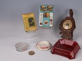 une petite horloge posée sur une table, à côté d'un paquet de cigarettes