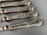 five silverware spoons with ornate designs on them on a table
