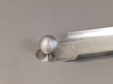 a golf ball on a silver tray with a golf ball on top of it