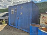 des toilettes portables bleues sur un parking, à côté d'une voiture blanche