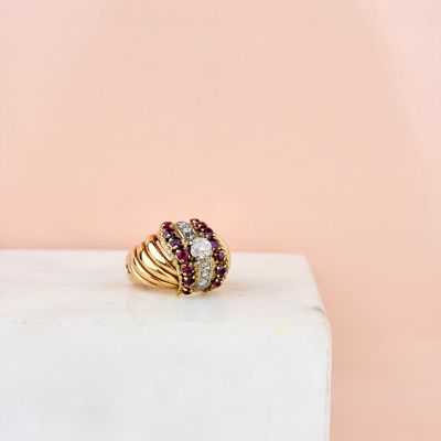 an image of a gold ring with rubies on top of a marble block