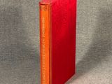 an orange book sitting on top of a table next to a gray wall