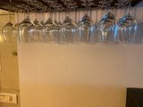 many wine glasses hanging from the wall above a wine glass rack