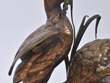 a bronze statue of a bird and a bird on a rock