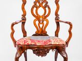 une chaise en bois avec une assise et des accoudoirs rembourrés d'un motif floral