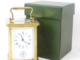 une petite horloge posée à côté d'une boîte sur une surface blanche