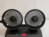 two small black fans sitting on top of a stand