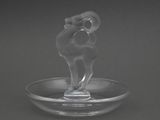a glass ram figurine sitting on a glass plate