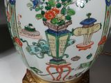 a vase and a plate on a table with a lamp on it