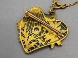 an image of a gold heart shaped pendant with a sword