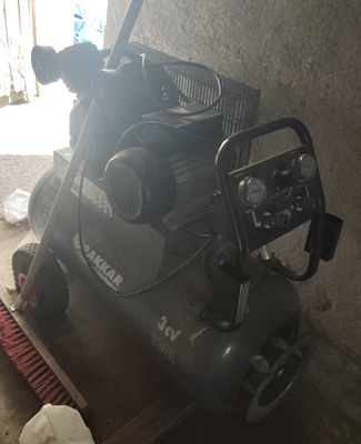 un petit compresseur d'air posé par terre à côté d'un balai