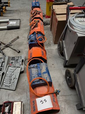 un long tuyau orange posé par terre à côté d'autres outils