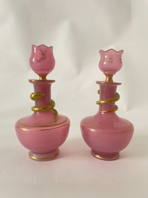 une paire de vases en verre rose avec des touches dorées sur fond blanc