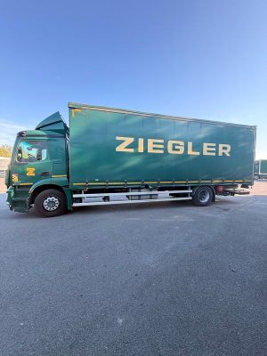 un camion vert garé sur un parking