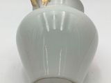 a white vase with a gold top sitting on a white surface