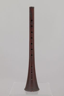 an old wooden flute on a clear stand on a white surface