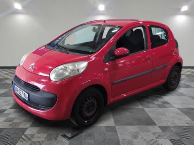 La petite voiture rouge est garée dans le garage, sur le sol à damier.