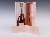 une bouteille de champagne dans un coffret rose, posée sur une table