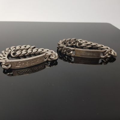 two silver bracelets with a chain on a black surface