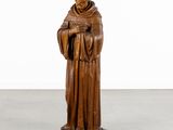 wooden statue of a monk holding a book in a white room