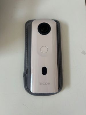 a white camera sitting on a table next to a cell phone