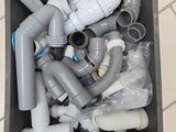 a box full of plastic pipes and fittings on a tiled floor