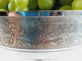 a silver bowl filled with green grapes on a table