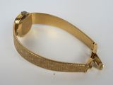 a close up of a gold bracelet on a white surface