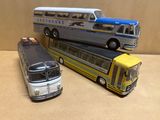 trois petits bus en plastique posés les uns à côté des autres sur une table