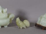 trois figurines en jade représentant des animaux et un oiseau, posées sur une table
