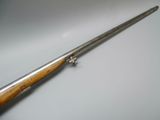 a close up of a rifle with a wooden handle on a white surface