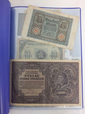 deux vieux billets de banque posés sur une table, à côté d'un rouleau de papier bleu