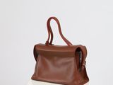 a brown leather handbag sitting on top of a white table