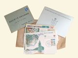 several envelopes and stamps sitting on top of a brown paper bag