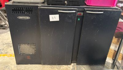 three black refrigerators are stacked on top of each other in a warehouse