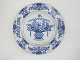 une assiette bleue et blanche sur laquelle est représenté un vase de fleurs