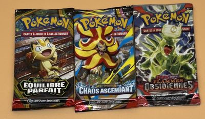 trois paquets de cartes à collectionner Pokémon posés sur une table