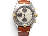 gros plan d'une montre sur une surface blanche avec un bracelet marron