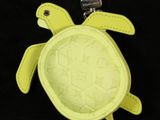 a yellow turtle keychain hanging on a black background