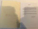 a shadow of a person holding a book in front of a white wall