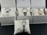 trois montres dans une boîte, avec un porte-clés posé sur une table noire